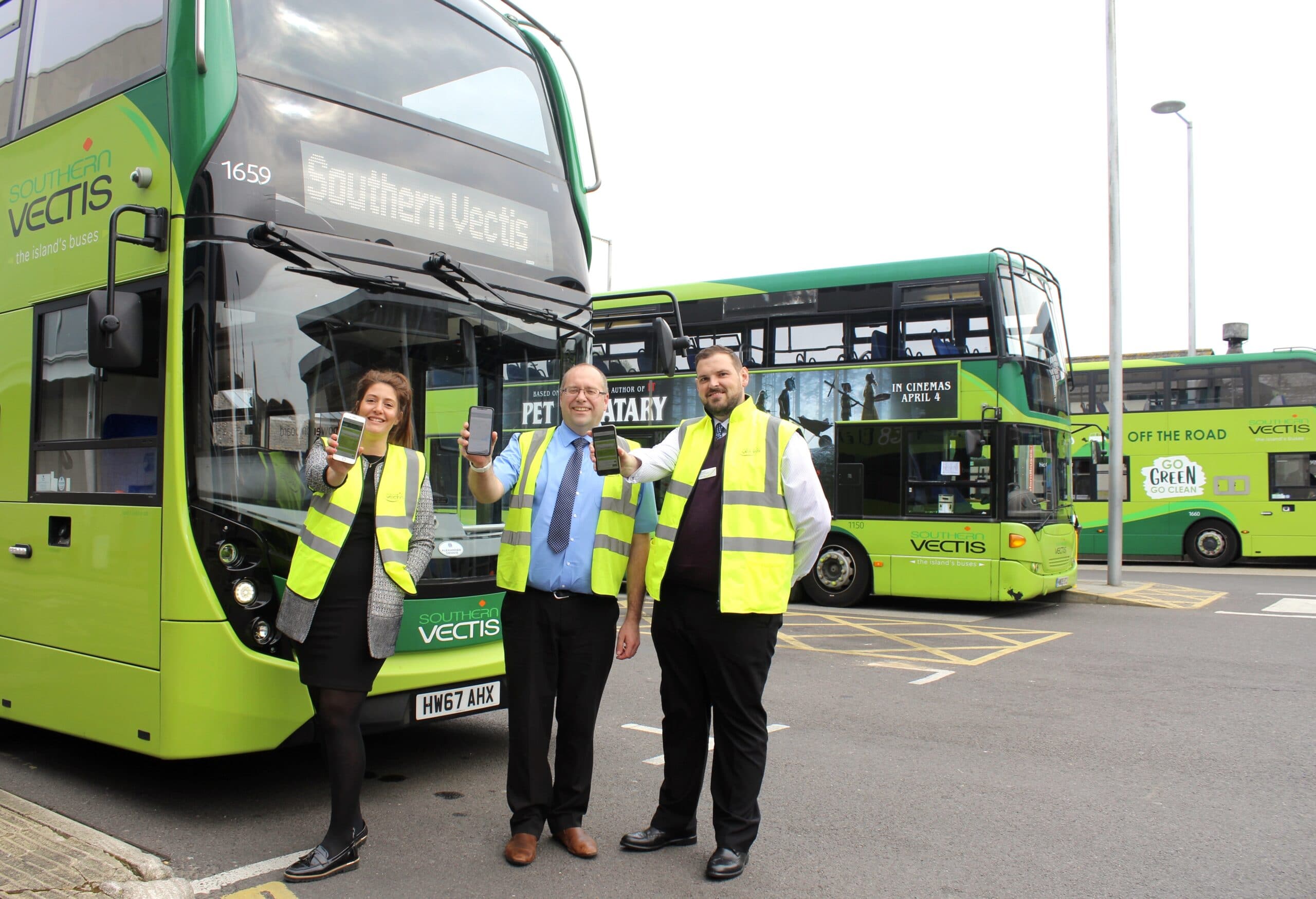 local Vectis team holding up mobiles with new website on display, in front of fleet