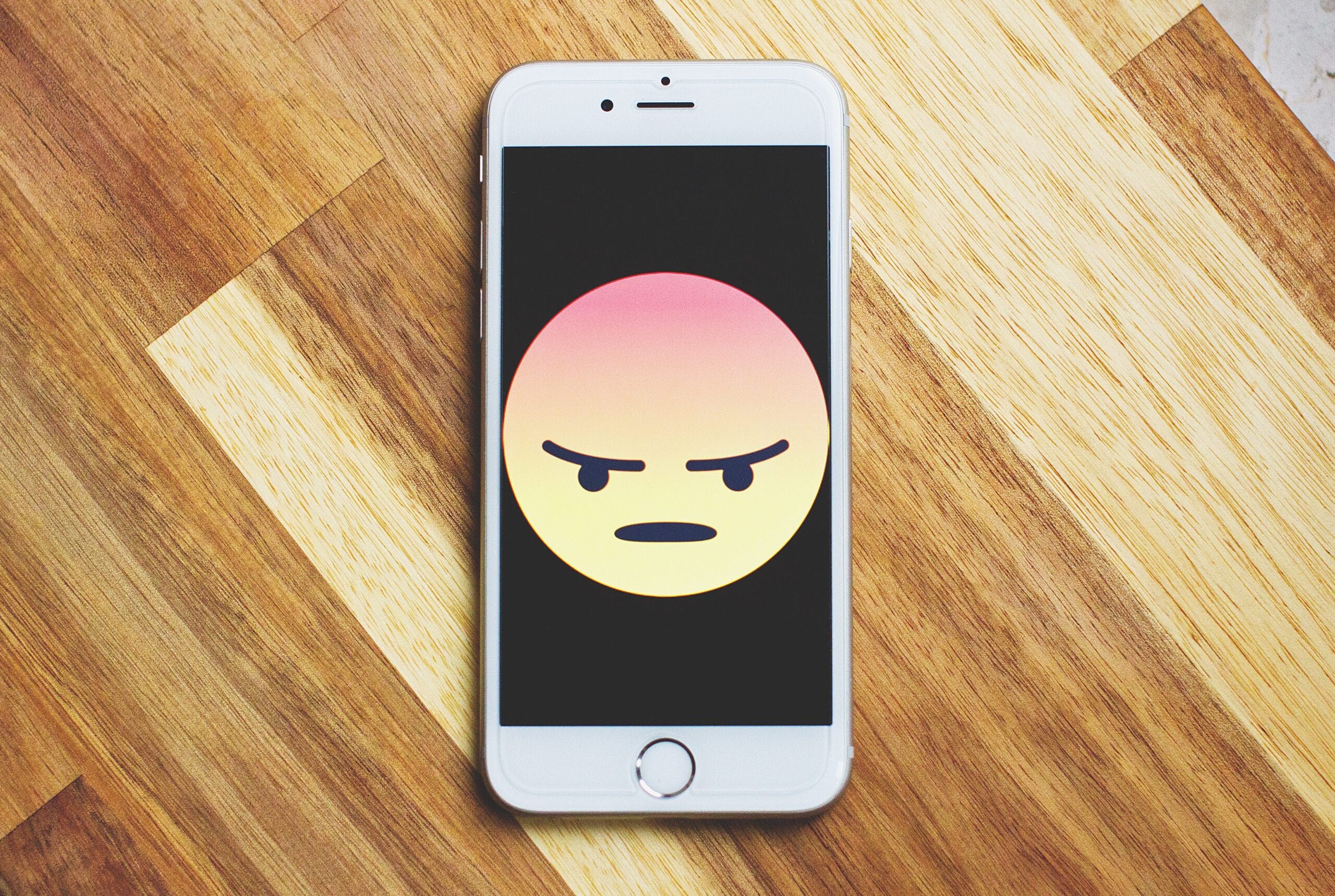 iPhone with large angry emoji