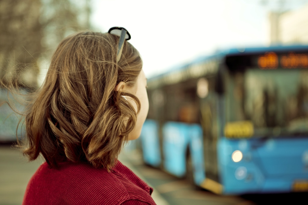 Young girl standing at a bus stop in the city