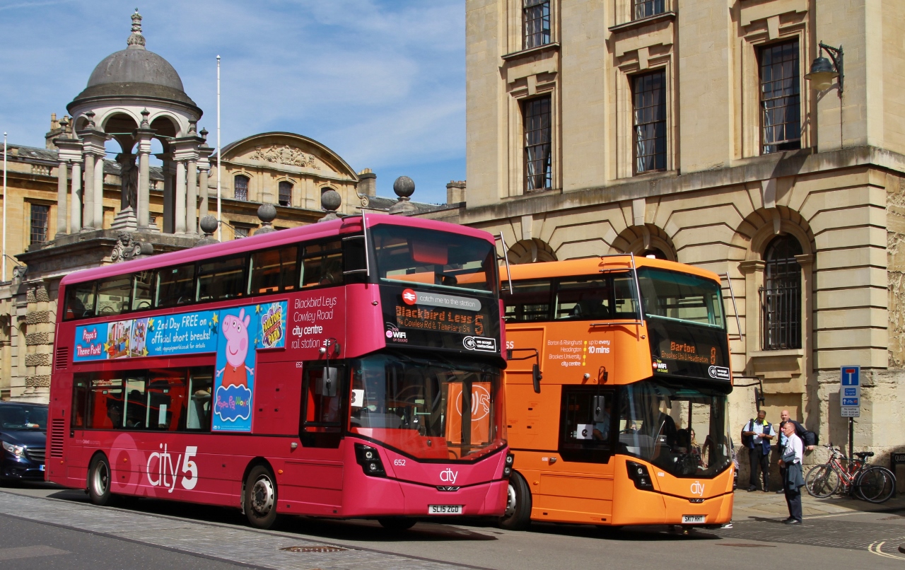 Two double decker buses parked outside an old building in Oxford