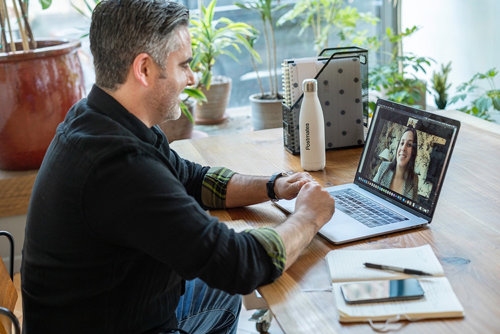 Man in an office on a video call to a woman using a laptop