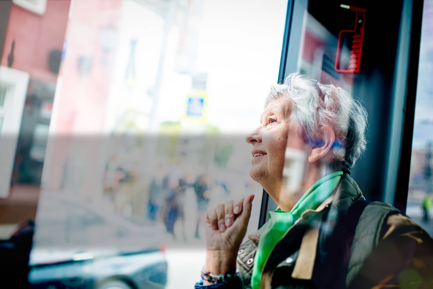 Senior woman sitting on a bus looking out of the window smiling