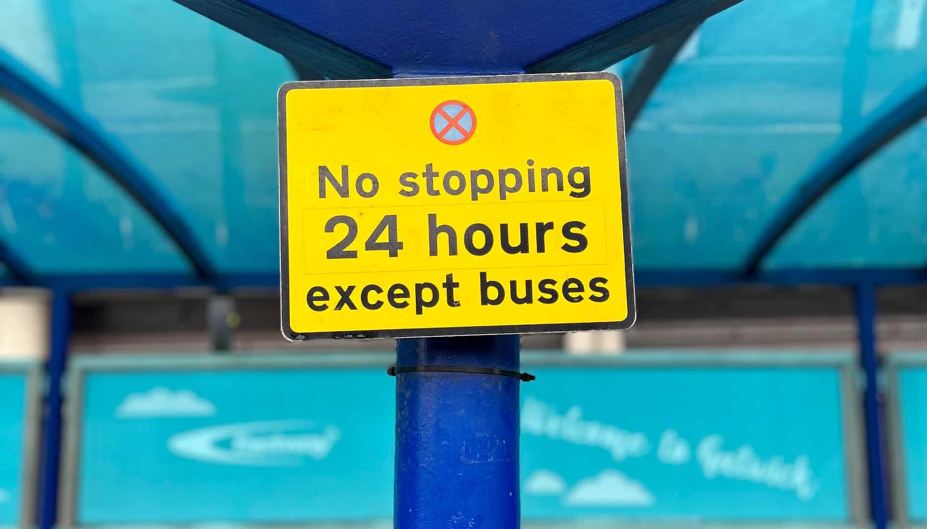 A road sign at a bus stop showing 