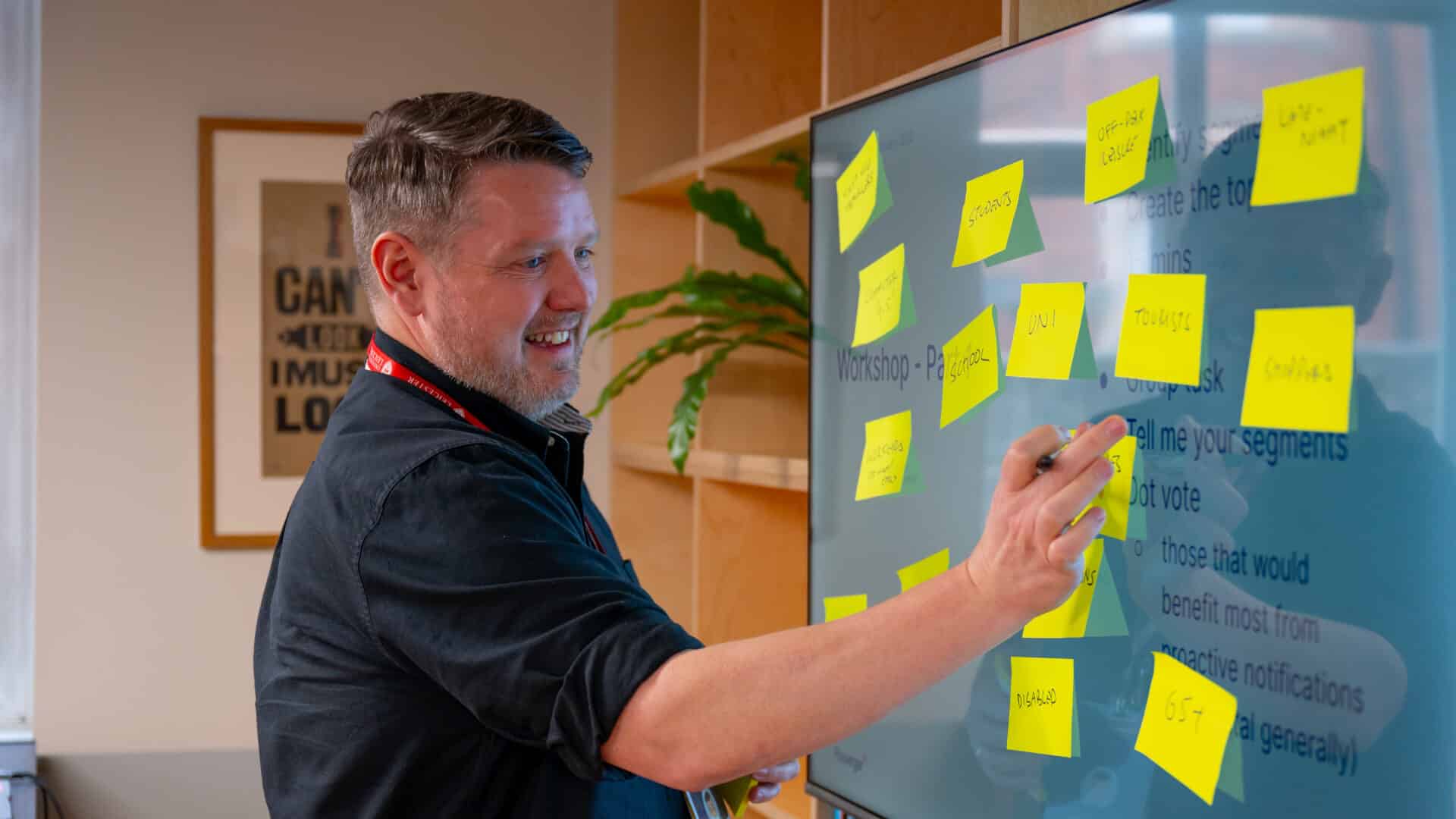 A man in front of a screen sticking on yellow post it notes
