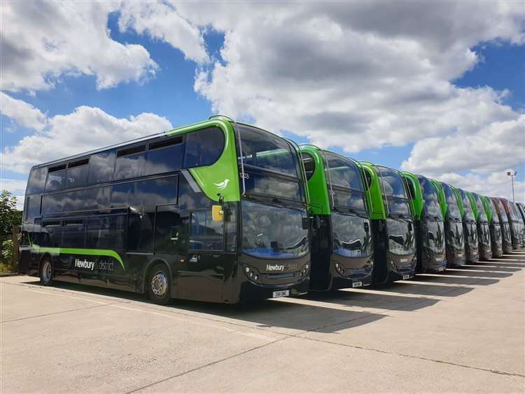 A row of double decker buses parked in the yard