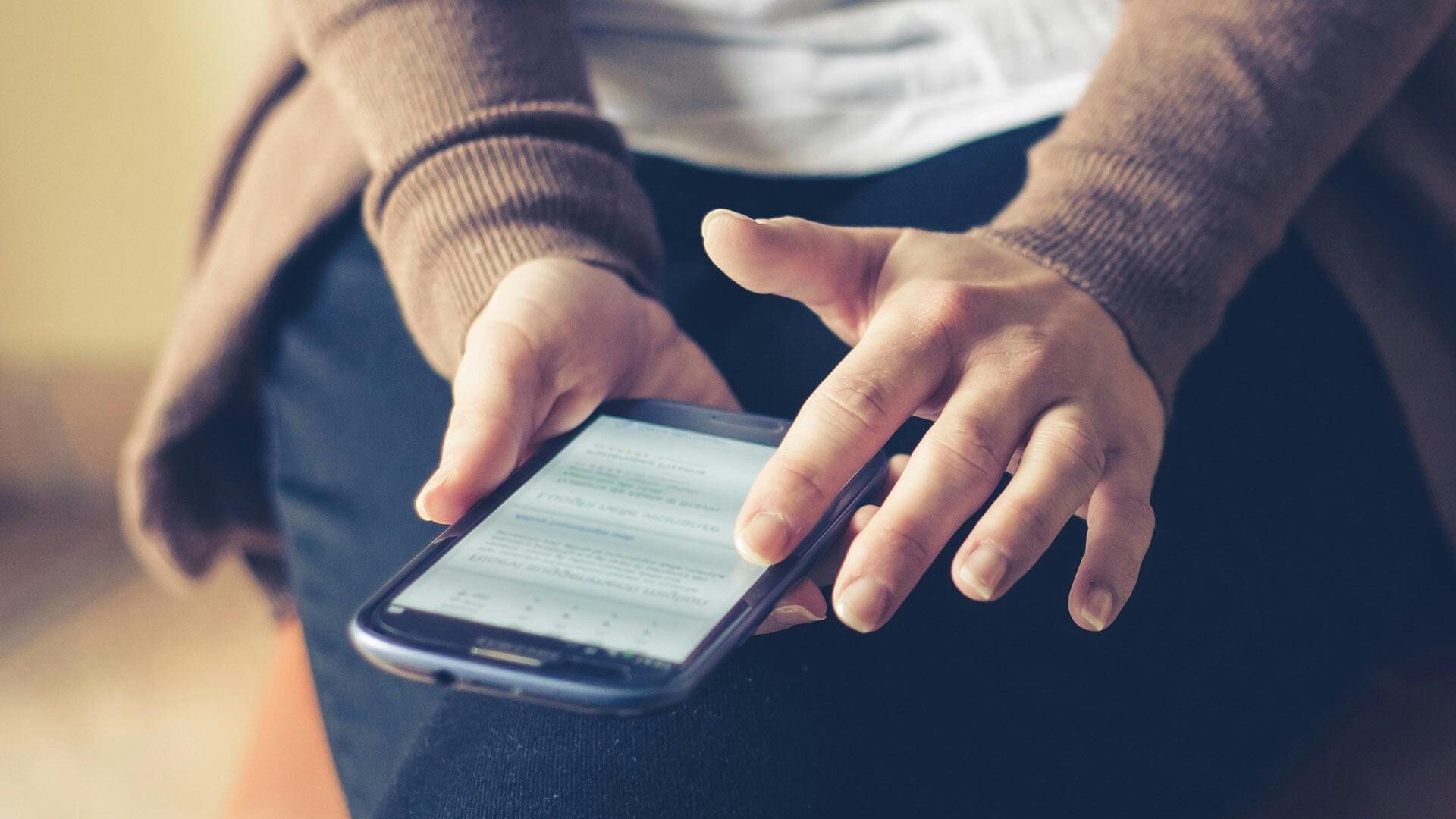 Person Holding Smartphone While Sitting